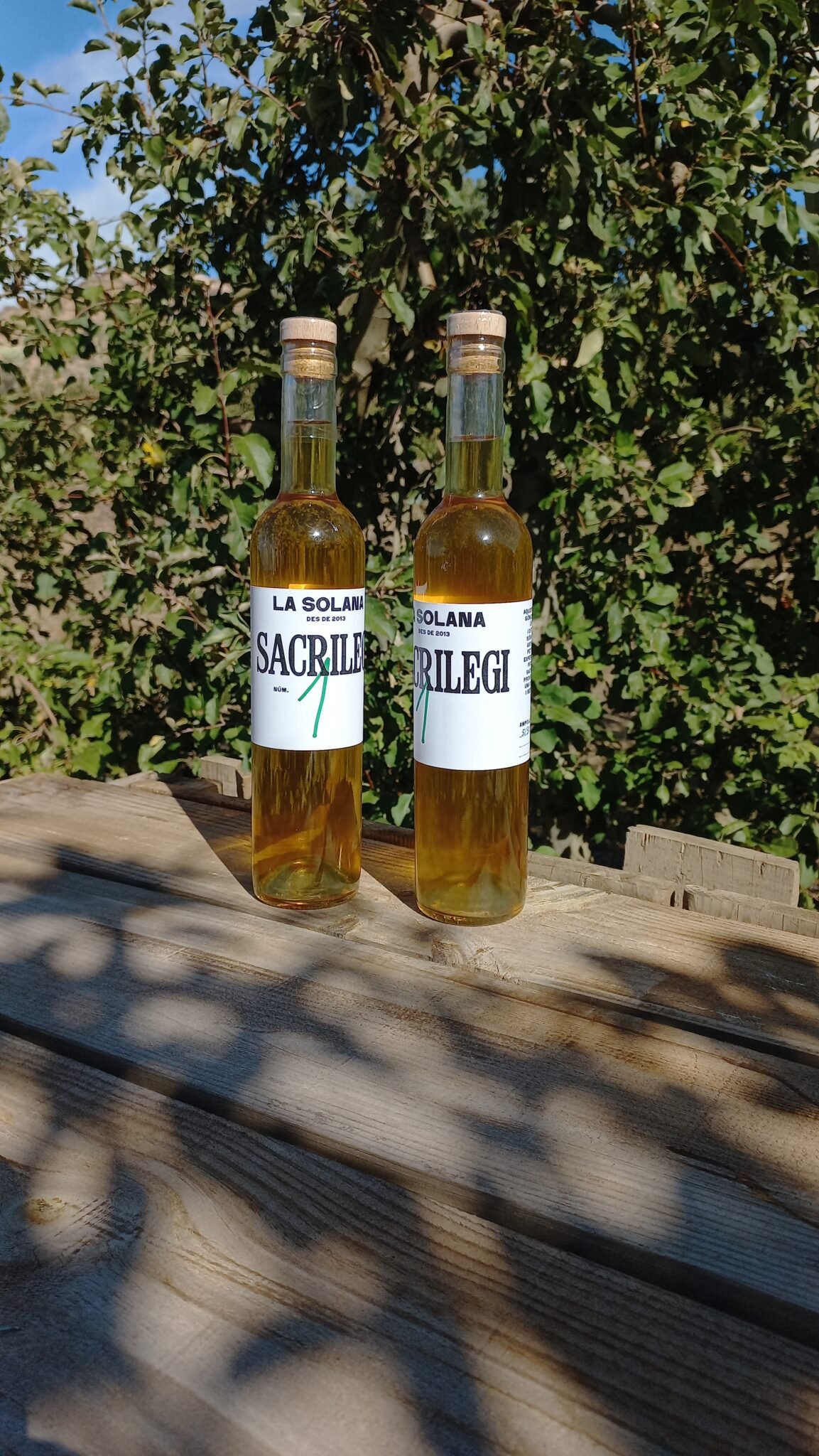 botellines de sidra sacrilegi la solana al sol en una mesa de madera